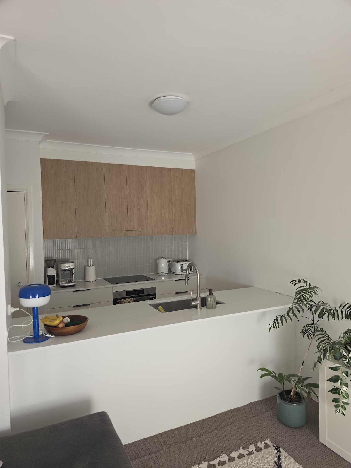 After: new kitchen with timber overhead cupboards and a white benchtop
