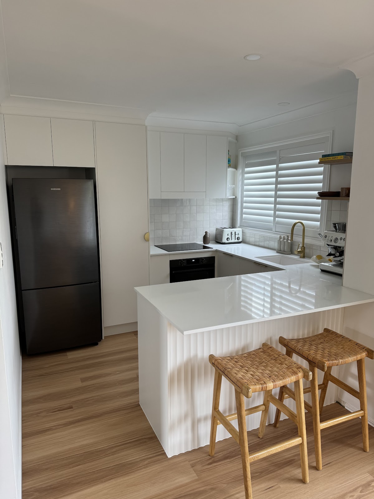 The same townhouse kitchen from the doorway, with a built-in fridge space and white overhead cupboards
